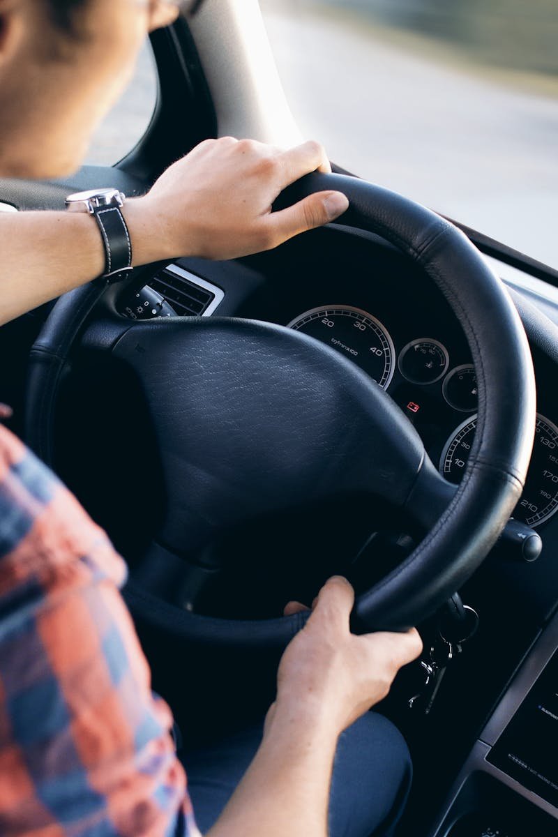 Close-up view of a man driving a modern car, showing dashboard and steering details.